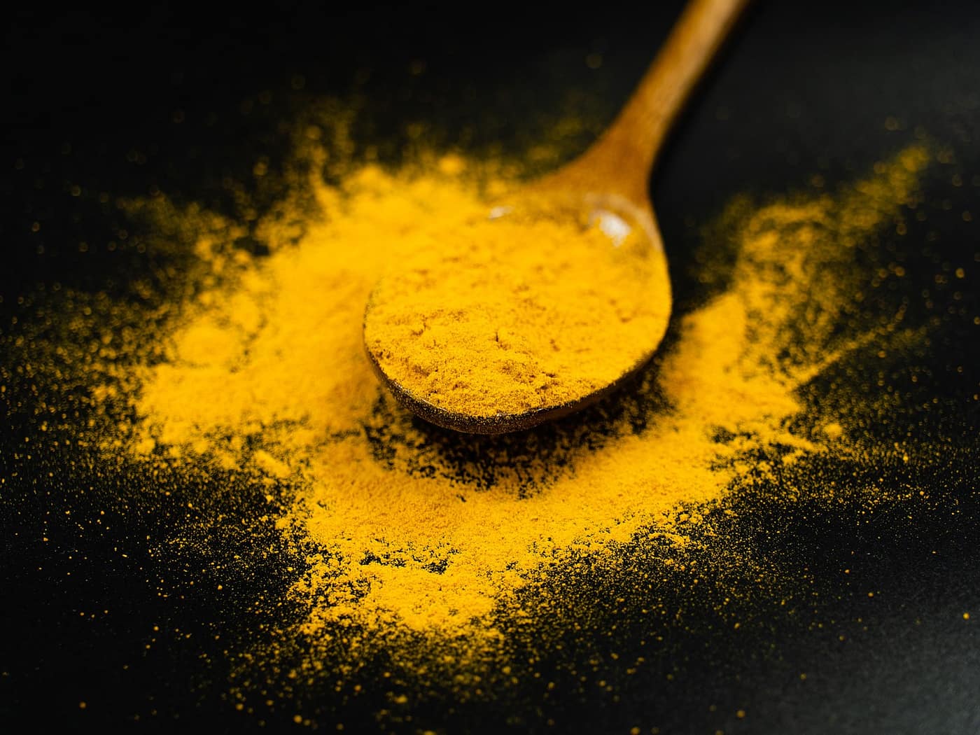 Ground turmeric on a wooden spoon
